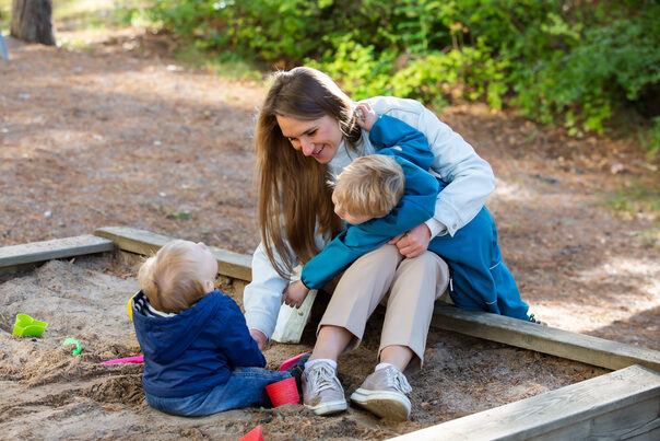 Alleinerziehende Mutter mit ihren Kindern im Sandkasten