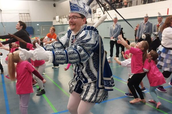 Karnevalsprinz tanzt mit Kindern in der Turnhalle