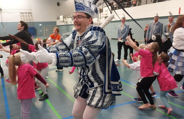 Karnevalsprinz tanzt mit Kindern in der Turnhalle